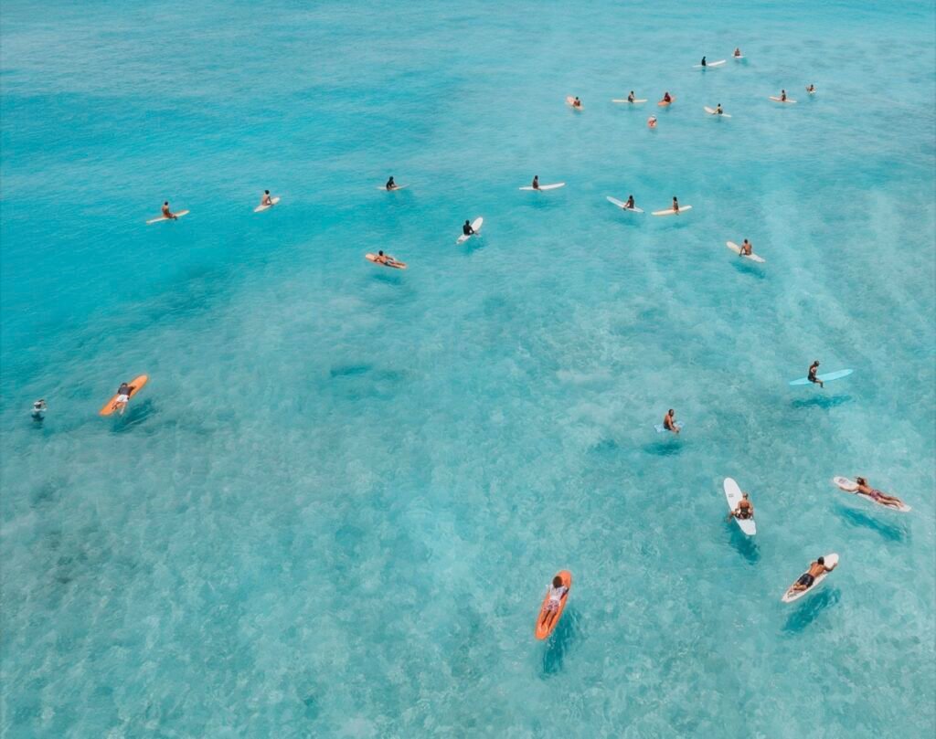 Aerial shot of surfers in the clear blue ocean water