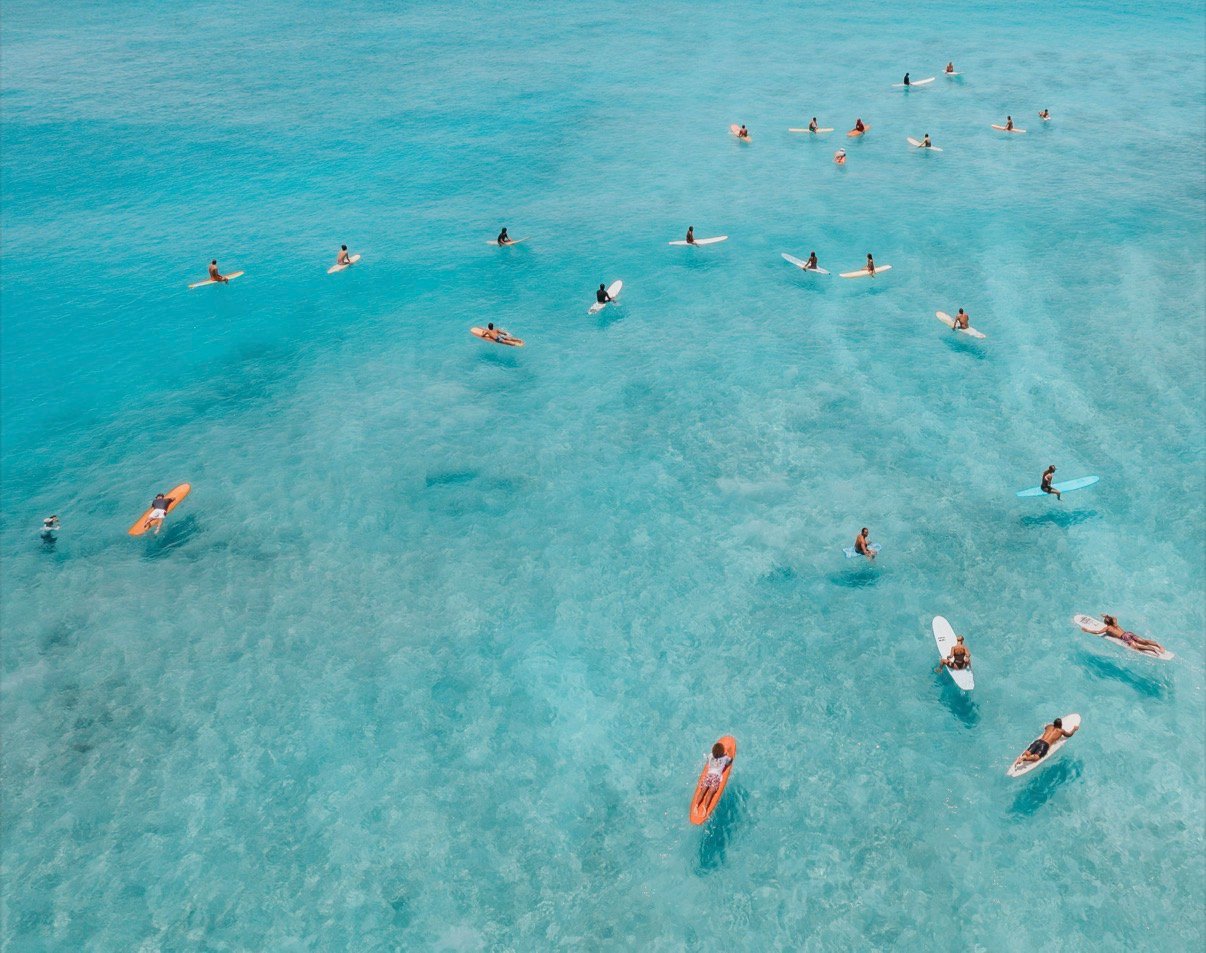 Aerial shot of surfers in the clear blue ocean water